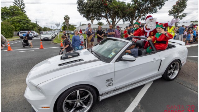 Image © Claude Thérond – used with permission Santa and elves riding in a white Mustang at the 2023 Pohutukawa Coast Santa Parade.