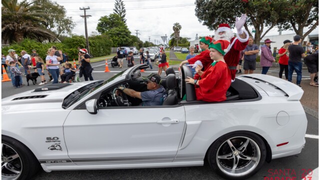 Image © Claude Thérond – used with permission Santa and elves riding in a white Mustang at the 2023 Pohutukawa Coast Santa Parade.