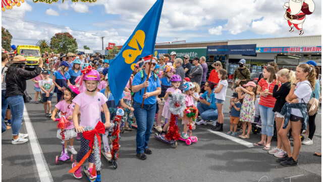 Image © Claude Thérond – used with permission Children on decorated scooters with flag at Pohutukawa Coast Santa Parade
