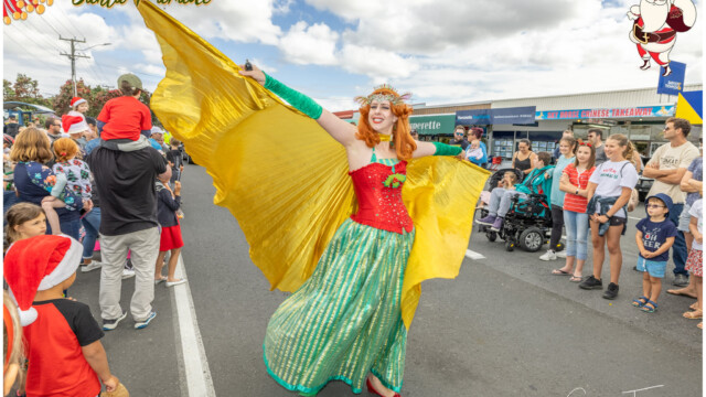 Image © Claude Thérond – used with permission Costumed performer with golden wings at Santa Parade