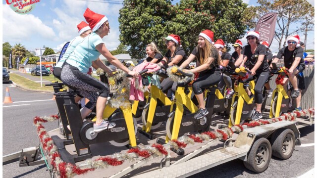 Image © Claude Thérond – used with permission Exercise bike group on decorated trailer in Santa Parade, Christmas celebration